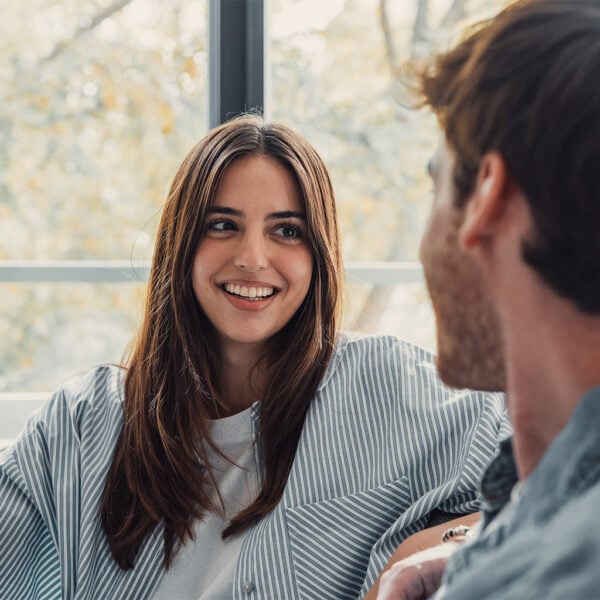 A smiling young woman and man engaging in a friendly discussion, showcasing interpersonal skills during a therapeutic counselling session at University Centre Peterborough (UCP).